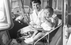 A woman and her child in a car, the child in a chair.