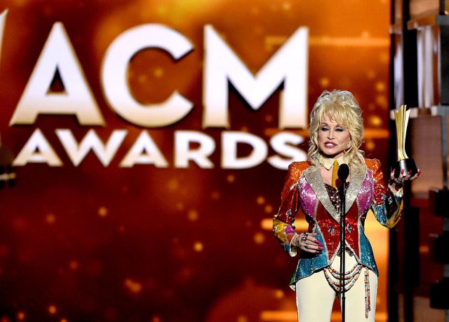 Dolly Parton holding up her ACM Award