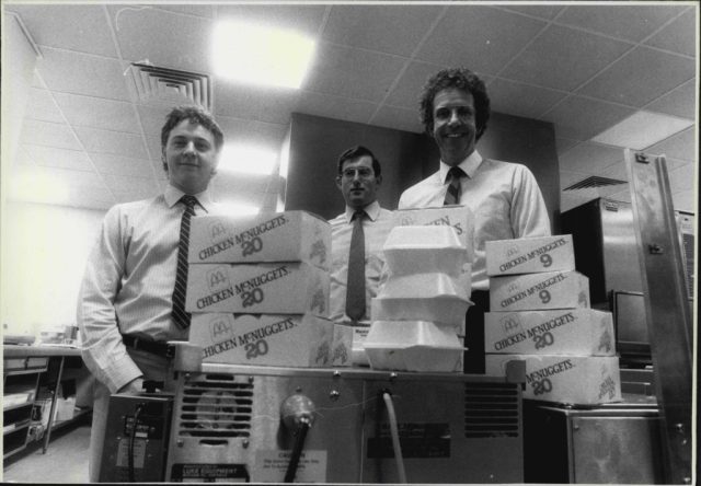 Three men standing in front of stacked styrofoam packaging
