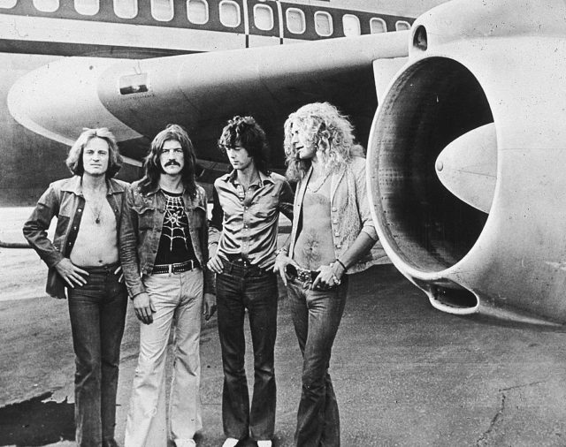 The band poses in front of their jet
