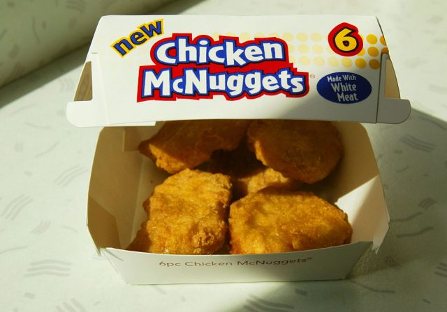 Four Chicken McNuggets in a cardboard container 