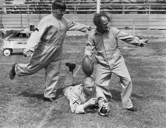 The Three Stooges clowning with a football on a football field, in a still from director Albert Rogell’s film ‘Start Cheering’. L-R: Moe Howard, his brother Curly Howard and Larry Fine. (Photo Credit: Hulton Archive/Getty Images)