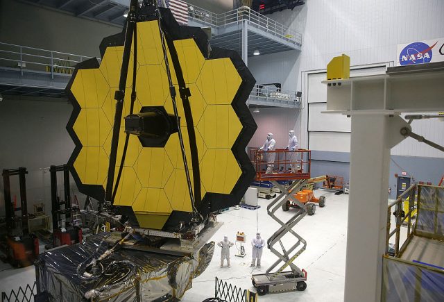 Scientists standing below the James Webb Space Telescope