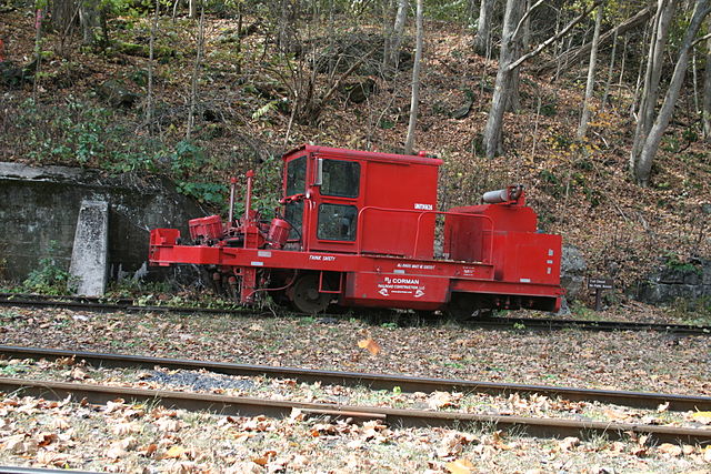 Red train equipment beside a hill
