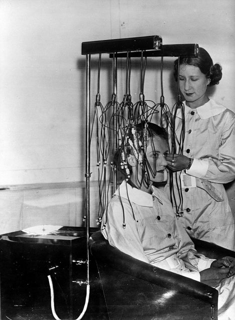 Woman putting another woman's hair into a perm machine