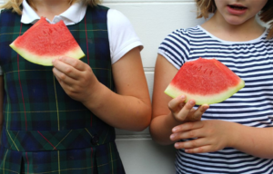 two people holding slices of watermelon
