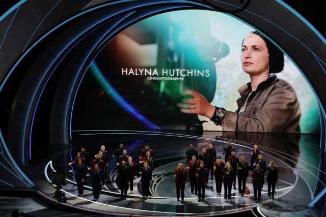 Individuals standing in front of a screen with Halyna Hutchins' image on it