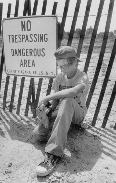 Niagara Falls, N.Y.: Joel Guagliano, 11, sits dejected Wednesday in the Love Canal section of Niagara Falls. Chemicals once dumped in the now-residential area are seeping through the ground and the New York State Health Department has urged some residents to leave the area until the problem can be resolved. (Photo Credit: Bettmann / Contributor)