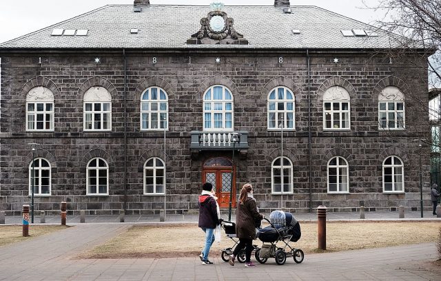 People walk outside of the Icelandic Parliament building in downtown Reykjavik (Photo Credit: Spencer Platt/Getty Images)