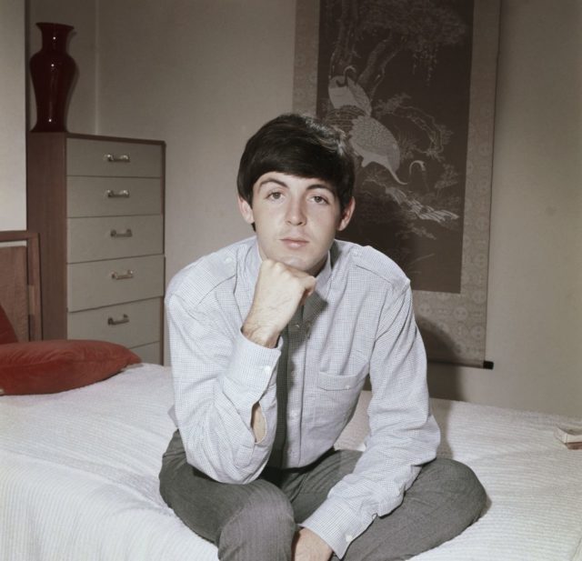 Portrait of Paul McCartney sitting on a bed
