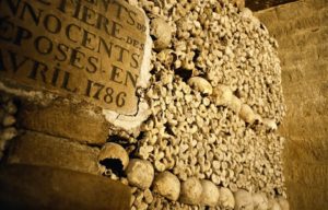 Wall of human skulls and femurs surrounding a sign