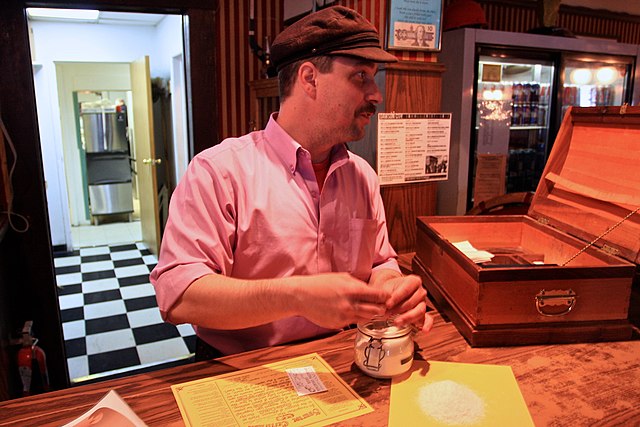 Man sitting at a wooden table while holding a mummified toe