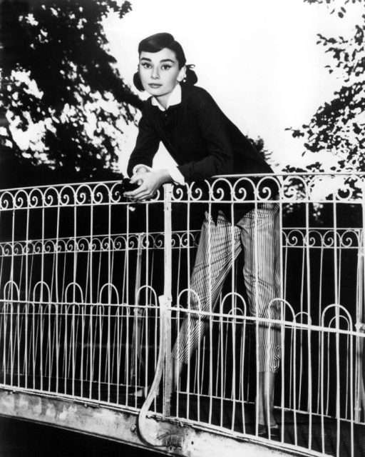 Audrey Hepburn leaning against the wall of a bridge