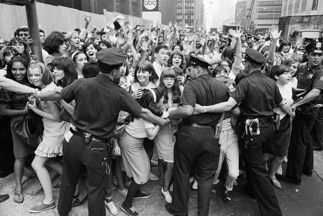 Police officers holding back a crowd of screaming fans