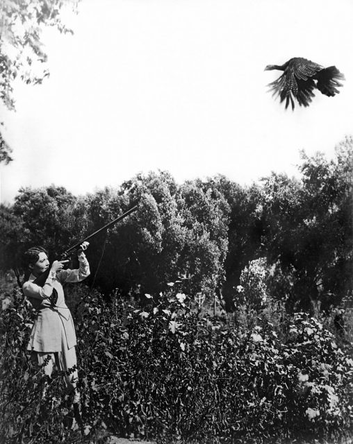 Dorothy Sebastian aiming a shotgun at a flying turkey