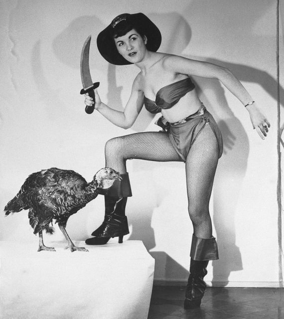 Flo Bondi standing above a turkey dressed as a pirate