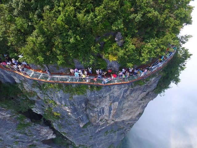 Tourists walk on a glass-bottomed skywalk on the Panlong (meaning coiling dragon) Cliff on Tianmen Mountain (Photo Credit: Feature China / Barcroft Media via Getty Images)
