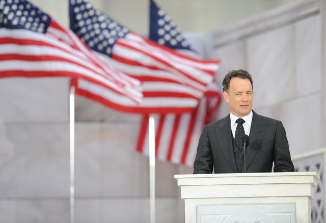 Tom Hanks gives a speech in front of American flags