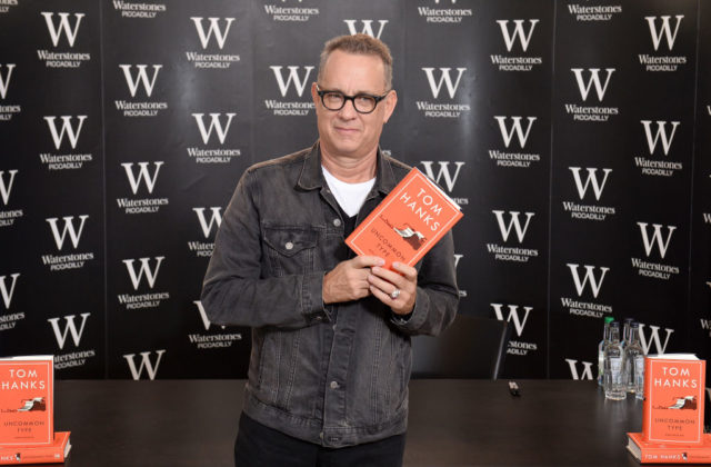 Tom Hanks holding up a copy of his book, 'Uncommon Type'