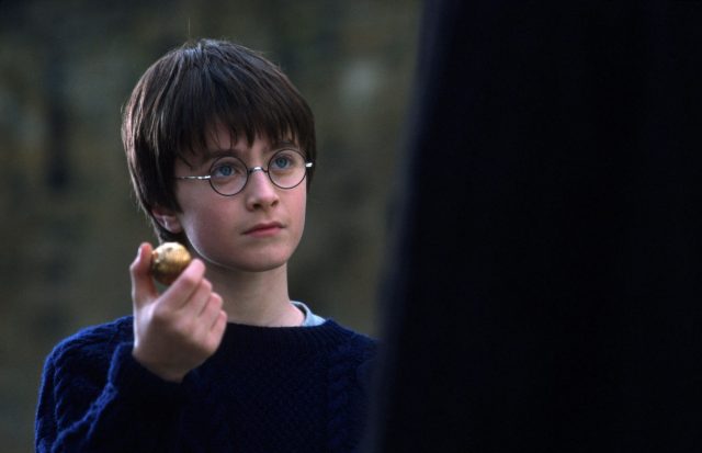 Harry Potter holding up the Golden Snitch for Oliver Wood