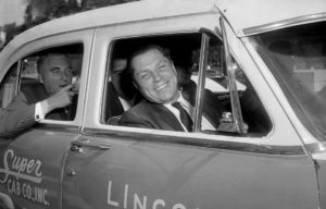 Jimmy Hoffa smiling out the front passenger window of car