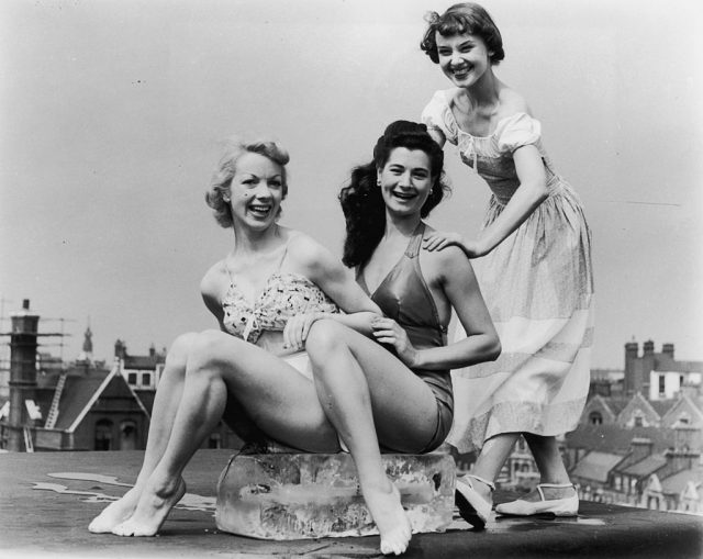 Aud Johannsen and Enid Smeeden sitting while Audrey Hepburn stands over them