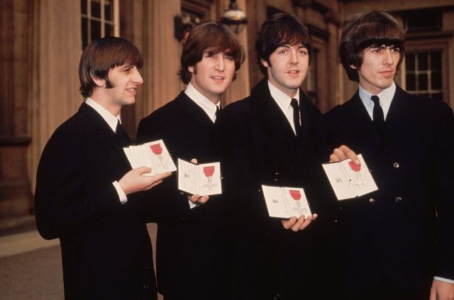 Members of the Beatles holding up their MBE's