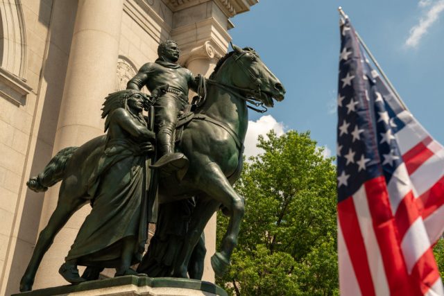 Theodore Roosevelt statue with an American flag beside it