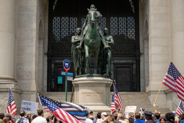 Protestors standing before the Theodore Roosevelt statue
