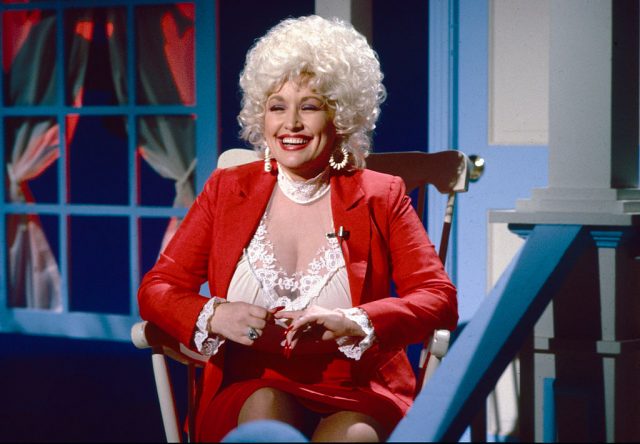 Dolly Parton sitting on the front porch of a house