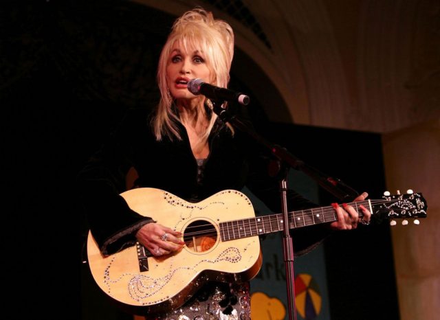 Dolly Parton performing on stage with a guitar
