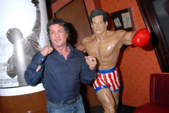 Sylvester Stallone standing with a statue of his 'Rocky' character