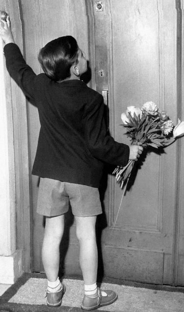 Boy, holding a bouquet of flowers for his mother, rings the bell