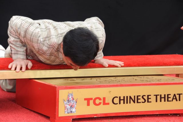 Jackie Chan sticking his nose in wet cement 