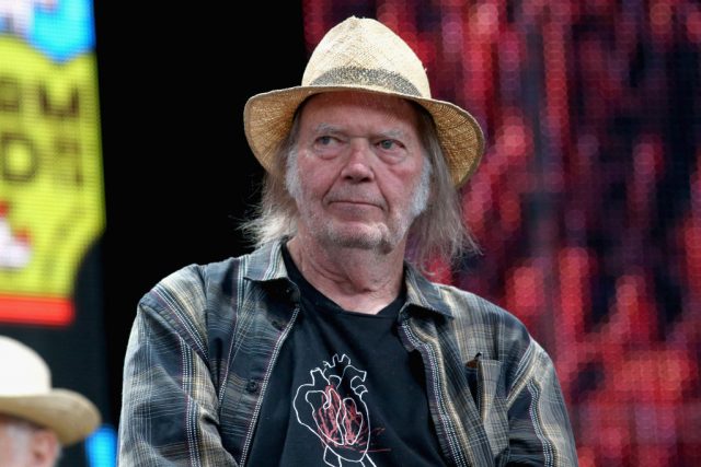 Neil Young sitting during a press conference
