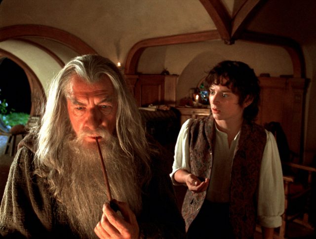 Frodo Baggins watching as Gandalf the Grey smokes a pipe