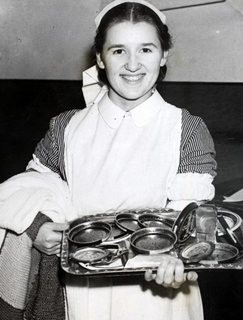 A nurse carrying a tray loaded with ashtrays