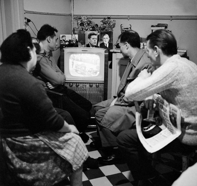 A family gathers in front of the television