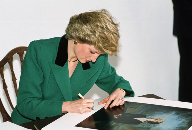 Diana, Princess of Wales signing an official of herself, taken by Lord Snowdon, at the Castle of St George in Lisbon (Photo Credit: Tim Graham Photo Library via Getty Images)