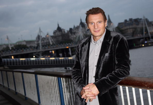 Liam Neeson poses by the River Thames