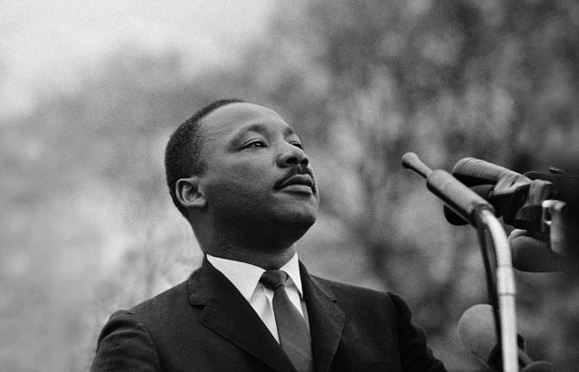 Martin Luther King Jr. standing in front of microphones