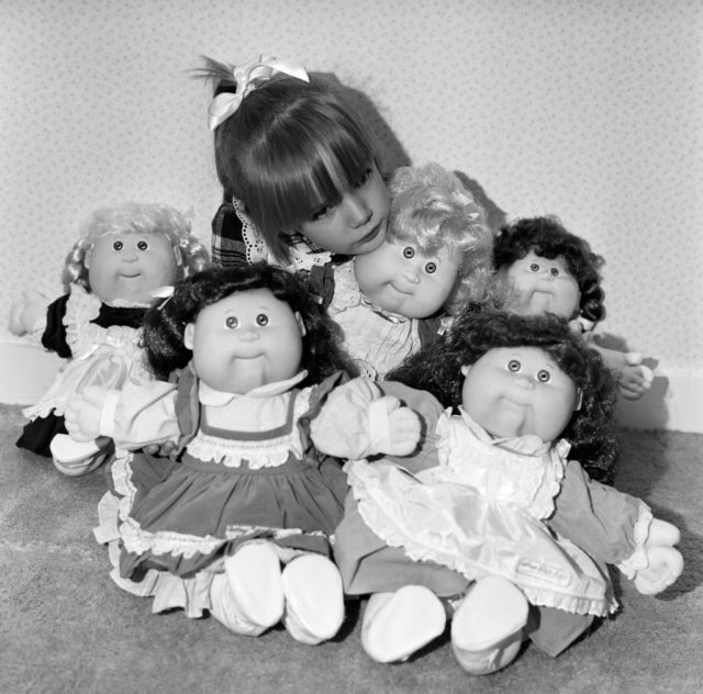 Young girl surrounded by five Cabbage Patch Kids dolls