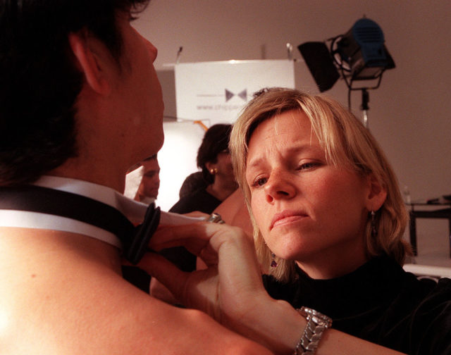 Woman putting a shirt collar on a Chippendales member