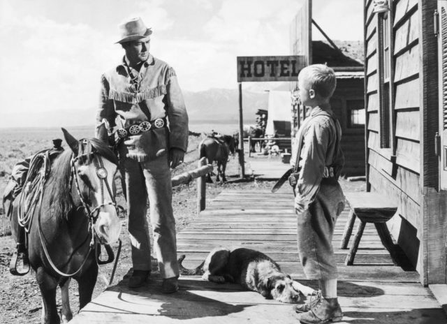 Alan Ladd stands next to a horse
