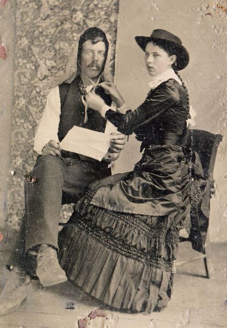 A cowgirl ties up her beau's hat