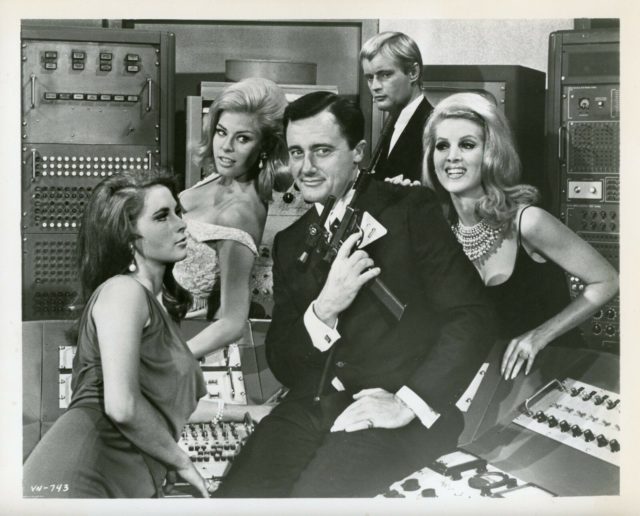 Napoleon Solo and Illya Kuryakin surrounded by women in a control room