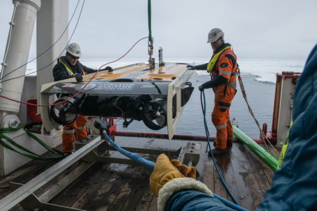 Frédéric Bassemayousse and J.C. Caillens standing with an AUV