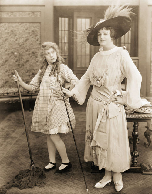 It is no particularly easy matter to impersonate the fashionable Julian Elting in a gingham dress such as demanded for the role of Rebecca of Sunnybrook Farm and with the aid of a mop handle, but even with this limited wardrobe Mary Pickford seems to succeed in doing this without any trouble. (Photo Credit: Bettmann / Contributor)