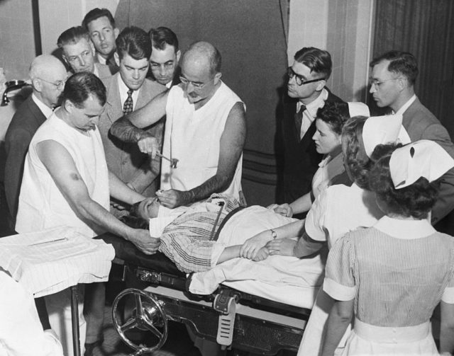 Walter Freeman performing a lobotomy while medical personnel watch
