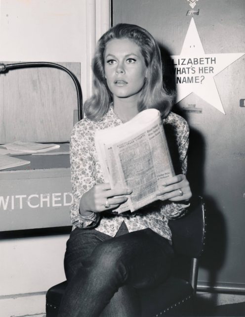 Actress Elizabeth Montgomery photographed on the set of "Bewitched" while reading a newspaper.